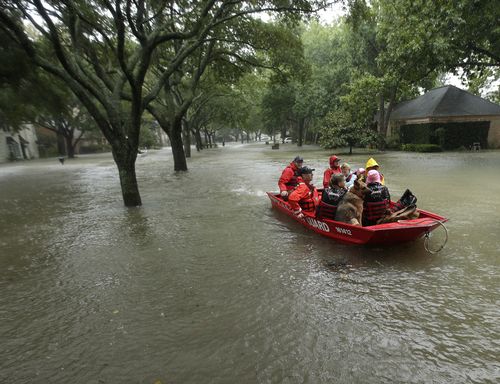 A Coast Guard rescue team evacuates people from a neighbourhood inundated by floodwaters. (AP) 