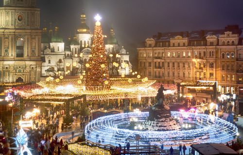 Crowds of people celebrate the New Year around the Christmas tree with the St. Sofia Cathedral in the background in Kyiv, Ukraine, Friday, Dec. 31, 2021