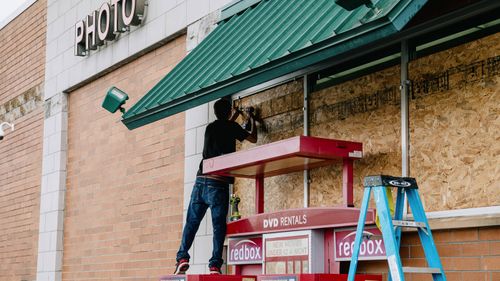 Workers board up a Walgreens store ahead of Hurricane Delta in Morgan City, Louisiana.