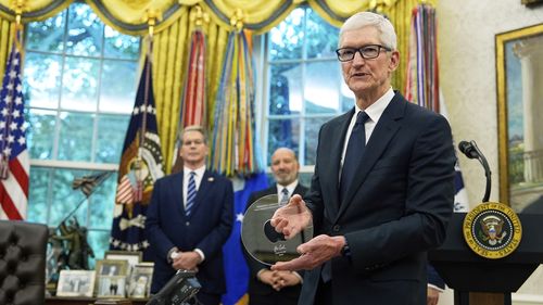 Apple CEO Tim Cook holds a gift from President Donald Trump in the Oval Office.