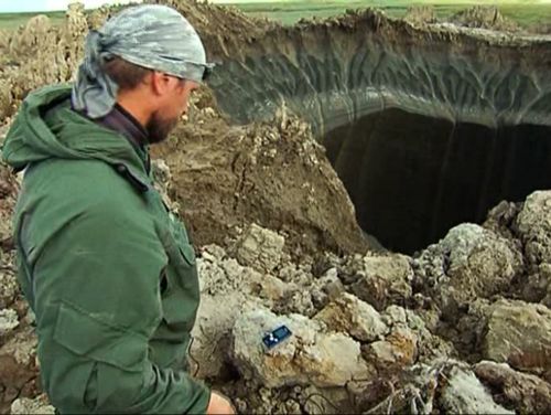 Andrei Plekhanov, a senior researcher at the Scientific Research Center of the Arctic, stands at a crater, discovered recently in the Yamal Peninsula. (AAP)
