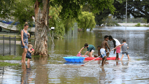 Children play in floodwaters in Ingham, Queensland. (AAP)