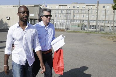 Rudy Guede, left, is greeted by an unidentified person as he leaves the penitentiary for a temporary release of thirty-six hours, in Viterbo, Italy, on June 25, 2016.