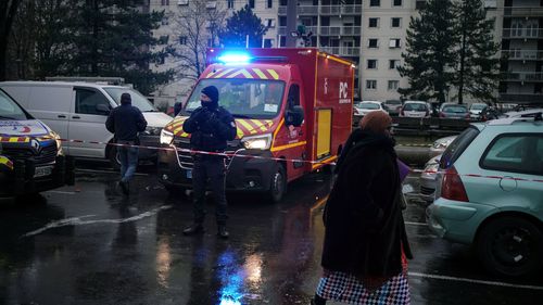 Un policier se tient près d'un camion de pompiers à côté d'immeubles d'habitation dans le quartier du Mas du Taureaum, à Vauls en Velin, à l'extérieur de Lyon, dans le centre de la France, le vendredi 16 décembre 2022.
