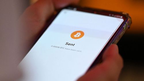 A person uses a mobile phone to make a payment with Bitcoin. 