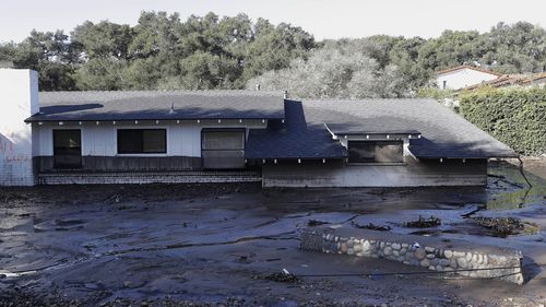 A home sits in mud and water in Montecito on Wednesday. (AAP)