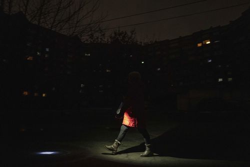 A woman lights up the road with a flashlight during blackout in Kyiv, Ukraine, Friday, February 3, 2023.