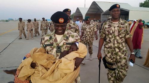 Maj- Gen. Rogers Nicholas, Theatre Commander, operation Lafiya dole, carries one of the freed school girls from the Government Girls Science and Technical College Dapchi. (AAP)