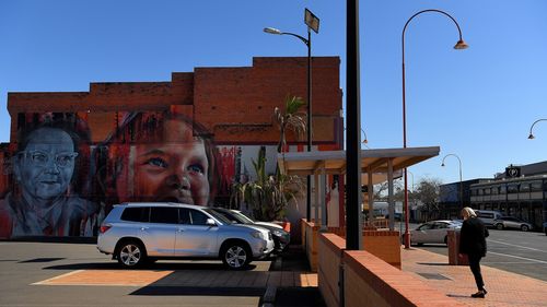 During the statewide lockdown a woman walks past a mural on the side of a building on Talbragar street in Dubbo, NSW.