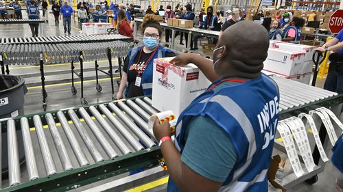 The first box containing the Johnson & Johnson COVID-19 vaccine heads down the conveyor to an awaiting transport truck at the McKesson facility in Shepherdsville, Kentucky.