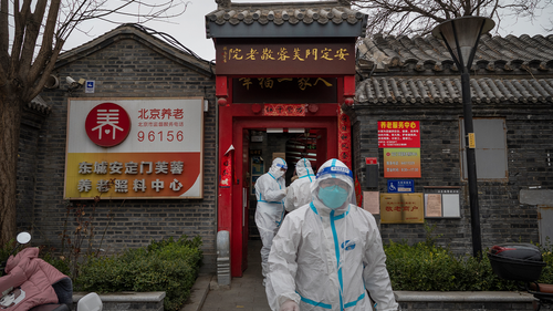 Health workers wear protective suits as they stand outside a seniors care home in a traditional courtyard house where they were performing nucleic acid tests to detect COVID-19 on local residents on March 25, 2022 in Beijing, China.