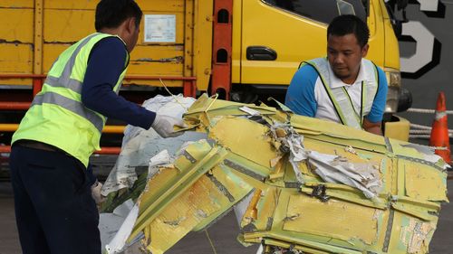 Officials move pieces of wreckage recovered from the crashed Lion Air jet for further investigation.