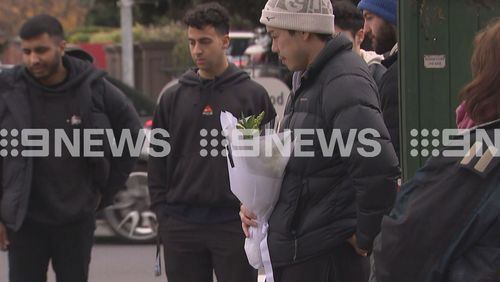 Friends gathered at a tribute site to lay flowers and offer each other support.