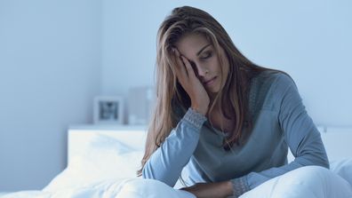 Depressed woman awake in the night, she is touching her forehead and suffering from insomnia