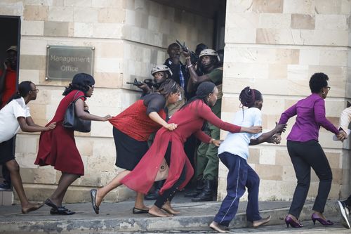 Terrified citizens hold on to each other as they flee to safety in front of armed police.