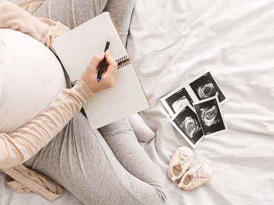 Pregnant woman writing in noteook