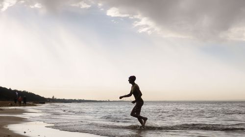 In this 2016 file photo a woman exits the water at Mentone Beach as a summer storm rolls across the city. 