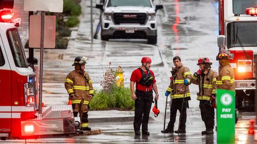 Firefighters look for one of two men swept into manhole during a rainstorm in downtown Omaha.