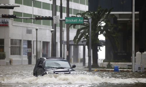 A vehicle drives on flooded Brickell Avenue in Miami. (AP)