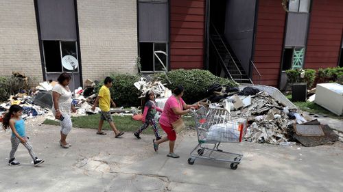 A family walks past debris, which includes a fridge. (AP)