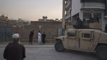 Afghans watch as Taliban fighters ride atop a humvee after detaining four men who got involved in a street fight in Kabul, Afghanistan
