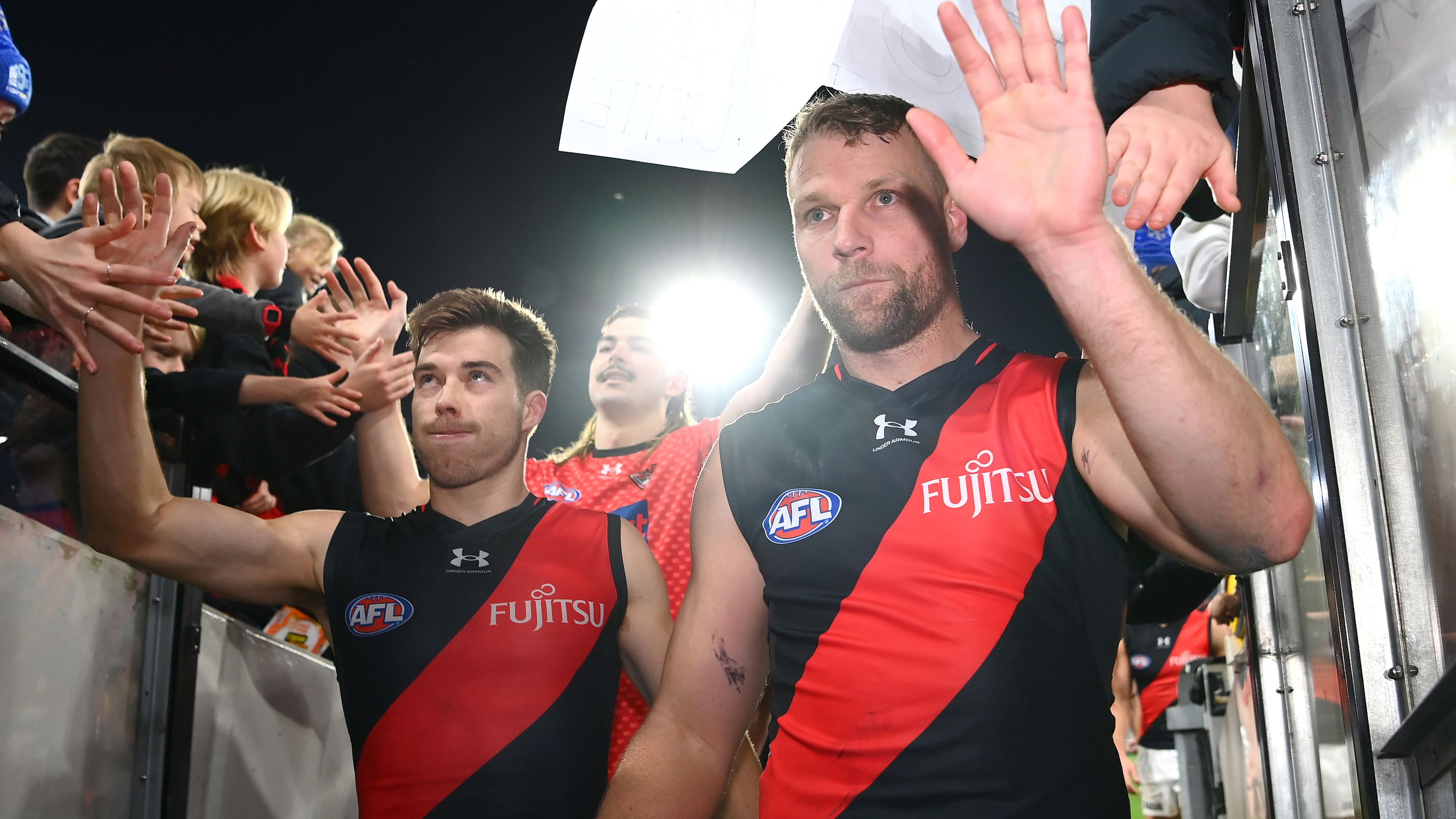 MELBOURNE, AUSTRALIA - JUNE 11: Zach Merrett and Jake Stringer of the Bombers high fives fans after winning the round 13 AFL match between Carlton Blues and Essendon Bombers at Melbourne Cricket Ground, on June 11, 2023, in Melbourne, Australia. (Photo by Quinn Rooney/Getty Images)