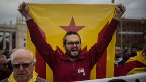 A protestor holds an independence flag during a demonstration in downtown Barcelona. (AAP)