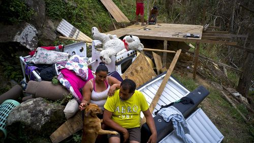 Yadira Sortre and William Fontan Quintero pose to what is left of their belongings, destroyed by Hurricane Maria while their children build a room to protect themselves from the elements, in the San Lorenzo neighbourhood. (AAP)