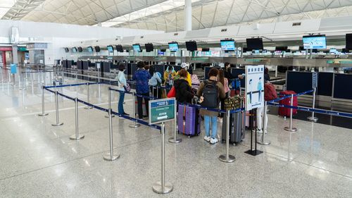 Travelers check in for a Singapore Airlines Ltd flight in the departure hall at Hong Kong International Airport.