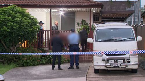 Police remove the body of a woman from the premises at Merrylands.