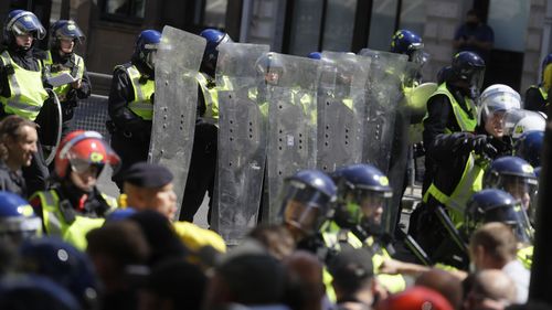 British police officers in riot gear scuffle with members of far-right groups protesting against a Black Lives Matter demonstration, in central London, Saturday, June 13, 2020.