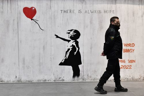 A man walks near a Banksy artwork