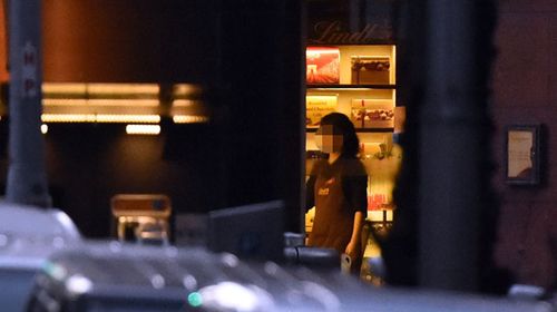 A hostage is seen going to the front door of the Lindt cafe to switch off the lights. (Getty)