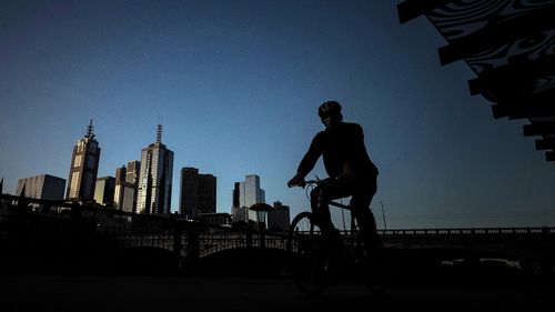 A man rides his bike along a very quiet Southbank in Melbourne, Australia.