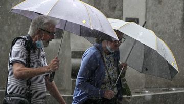 Pedestrians use umbrellas to shield the rain in Sydney, Wednesday, March 2, 2022, as parts of Australia&#x27;s southeast coast were inundated by the worst flooding in more than a decade. Floodwaters are moving south into New 