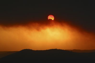 A partial solar eclipse through plumes of smoke over Broken Bay in New South Wales in 2002.