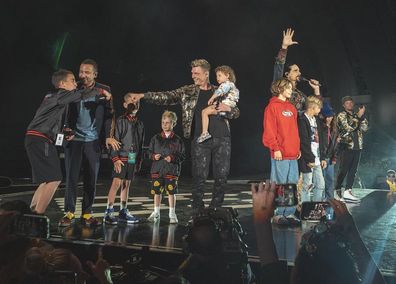 Backstreet Boys perform on stage with fans. 