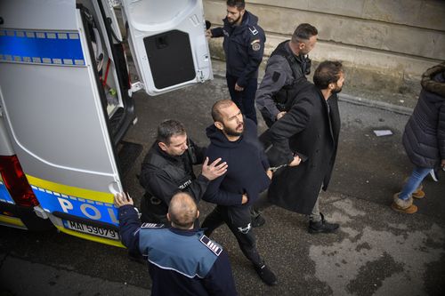 Police officers escort Andrew Tate, third from left, handcuffed to his brother Tristan, to the Court of Appeal after they appealed the decision to extend their arrest by another 30 days term in Bucharest, Romania, Wednesday, Feb. 1, 2023. 