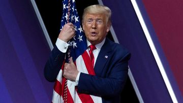 Donald Trump cuddles a flag at last year&#x27;s CPAC.