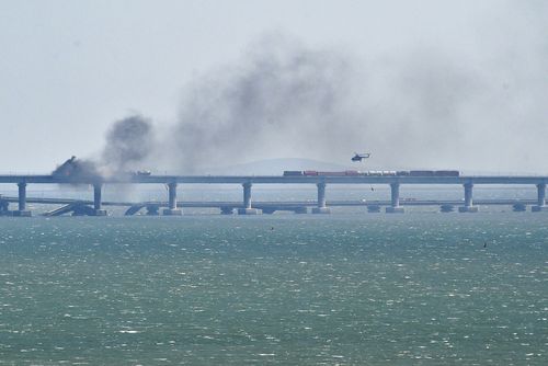 A helicopter flies to drop water to stop fire on Crimean Bridge connecting Russian mainland and Crimean peninsula over the Kerch Strait, in Kerch, Crimea, Saturday, Oct. 8, 2022. 