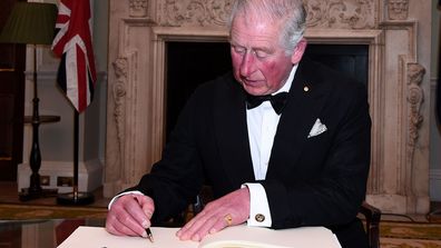 Prince Charles, Prince of Wales signs a book as he attends a dinner in aid of the Australian bushfire relief and recovery effort at Mansion House on March 12, 2020 in London, England