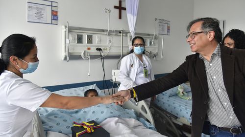 In this handout photo released by Colombian Presidential Press Office, Colombia's President Gustavo Petro greets a nurse tending to one of the four Indigenous children who survived an Amazon plane crash that killed three adults and then braved the jungle for 40 days before being found alive.