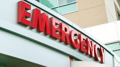 Large red EMERGENCY sign on hospital entrance. Raw original.