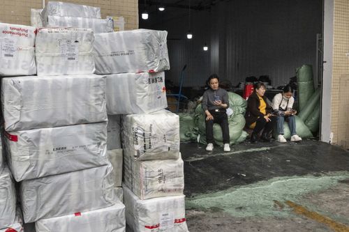 People outside a garment workshop where piles of Shein packages wait to be shipped in Guangzhou, China, Feb. 12, 2025. Shein and its rival Chinese e-commerce giant, Temu, coordinate much of their supply chains from the city. (Gilles Sabrié/The New York Times)