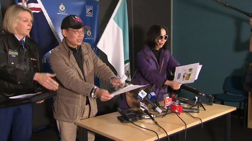 Mr and Mrs Yu desperately hand out pictures of their daughter to the media as they conclude their press conference. (9NEWS)