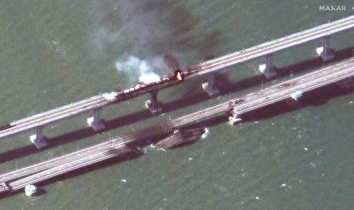 Cette image satellite fournie par Maxar Technologies montre des dommages au pont de Kertch, qui relie la péninsule de Crimée à la Russie traversant un détroit entre la mer Noire et la mer d'Azov, et des wagons en feu le samedi 8 octobre 2022. (Maxar Technologies via AP)