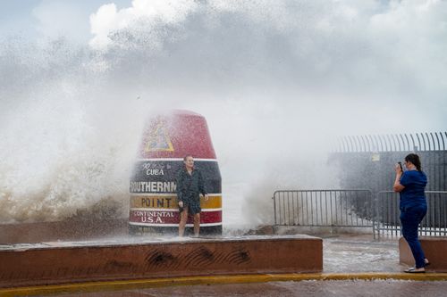 Les visiteurs de la bouée de Southernmost Point bravent les vagues renforcées par l'ouragan Idalia le mardi 29 août 2023, à Key West, en Floride.  