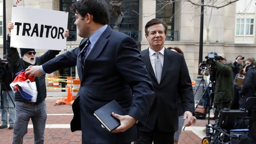 Paul Manafort (right) is greeted by a protester outside court. (AAP)