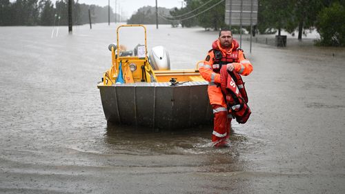 A member of the State Emergency Services (SES) prepares to take to flood water in Logan.