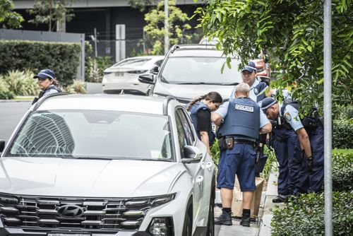 A polícia inspeciona um saco de evidências em Lidcombe.
